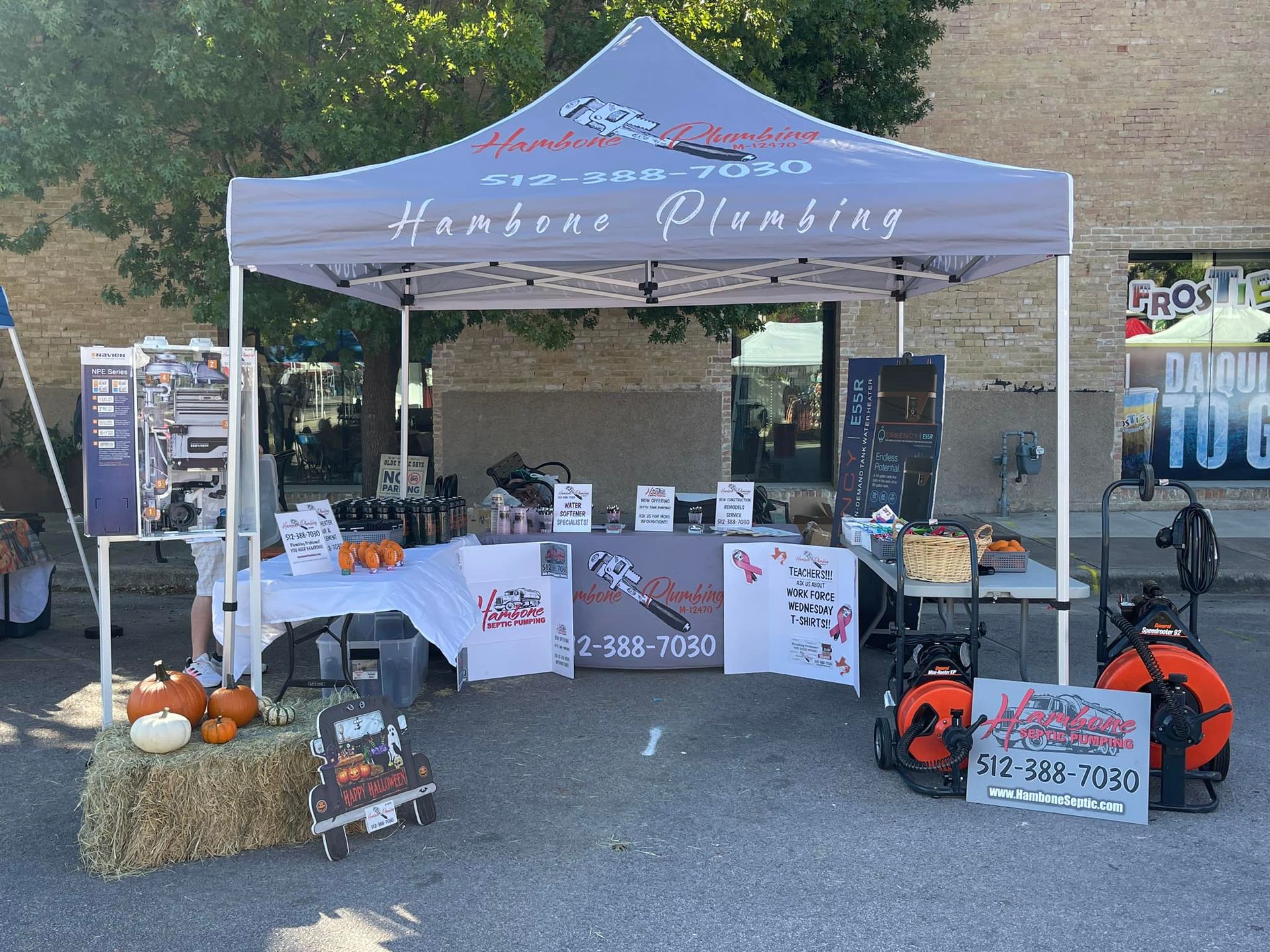 Camping vendor booth with blue tent, tables, and orange gear display outdoors