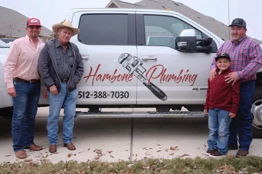 Plumbers posing beside a white van with “Hammond Plumbing” logo and phone number.