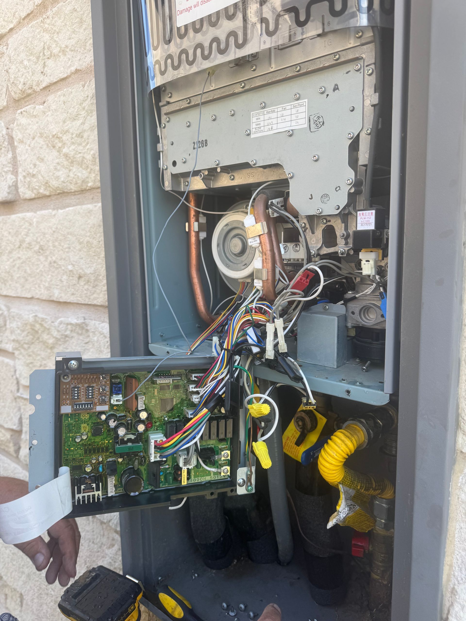 Open electrical meter box with exposed circuit boards and wiring on a wall outdoors