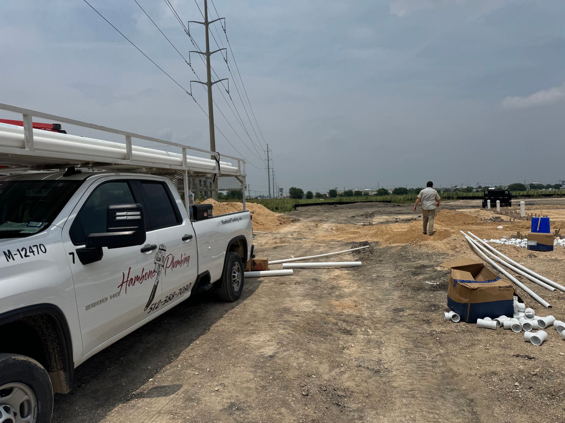 White pickup truck beside a dirt road at a utility worksite with power lines and scattered materials