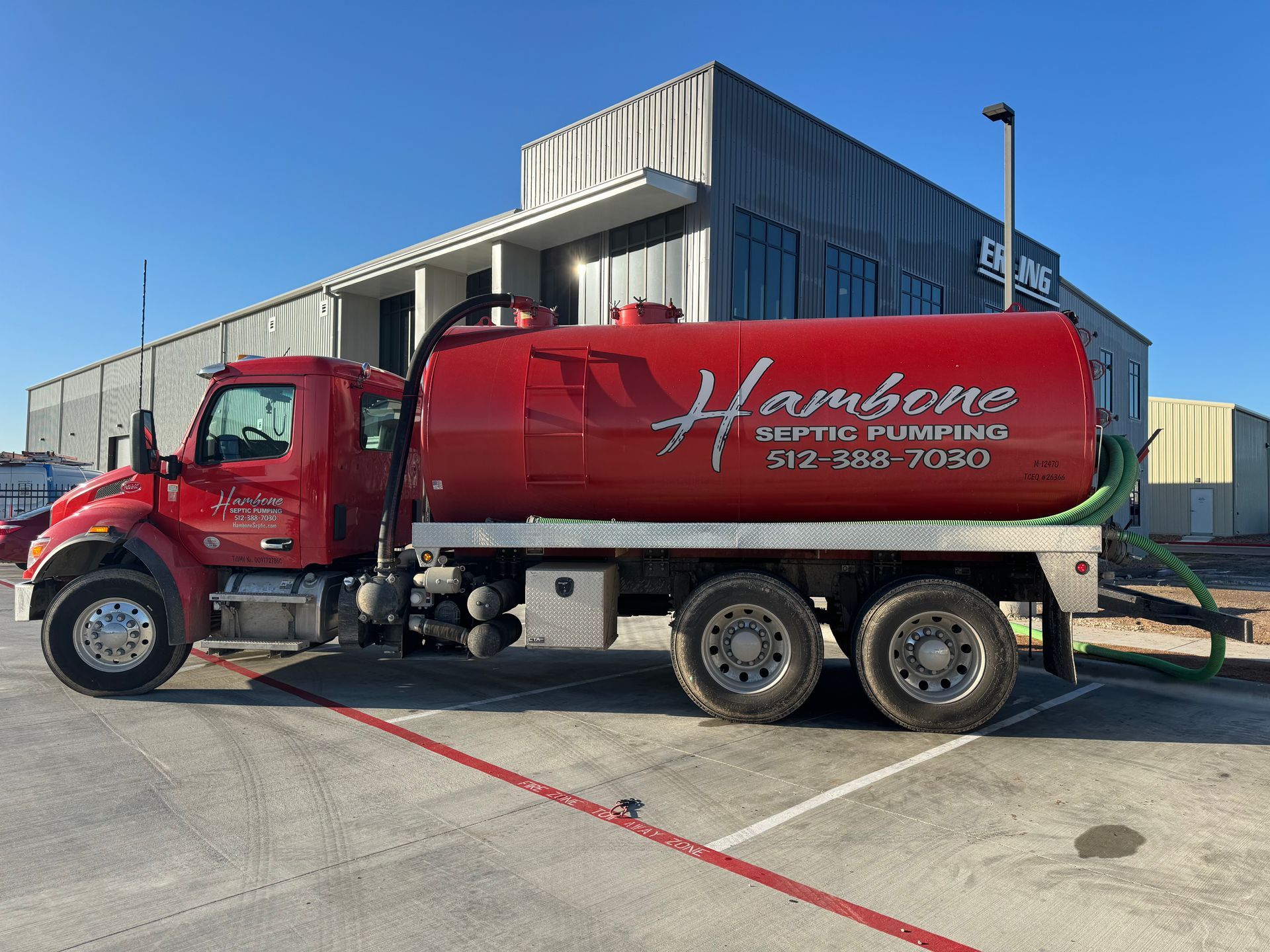 Red water truck with Hampton branding parked outside a warehouse on a sunny day
