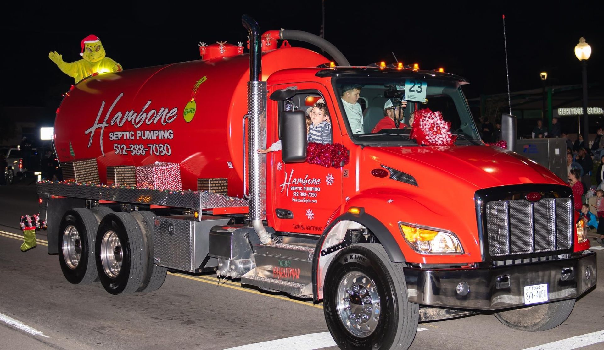 Red tanker truck with a shiny red cab parked at night, with a yellow mascot on top and a logo on the tank