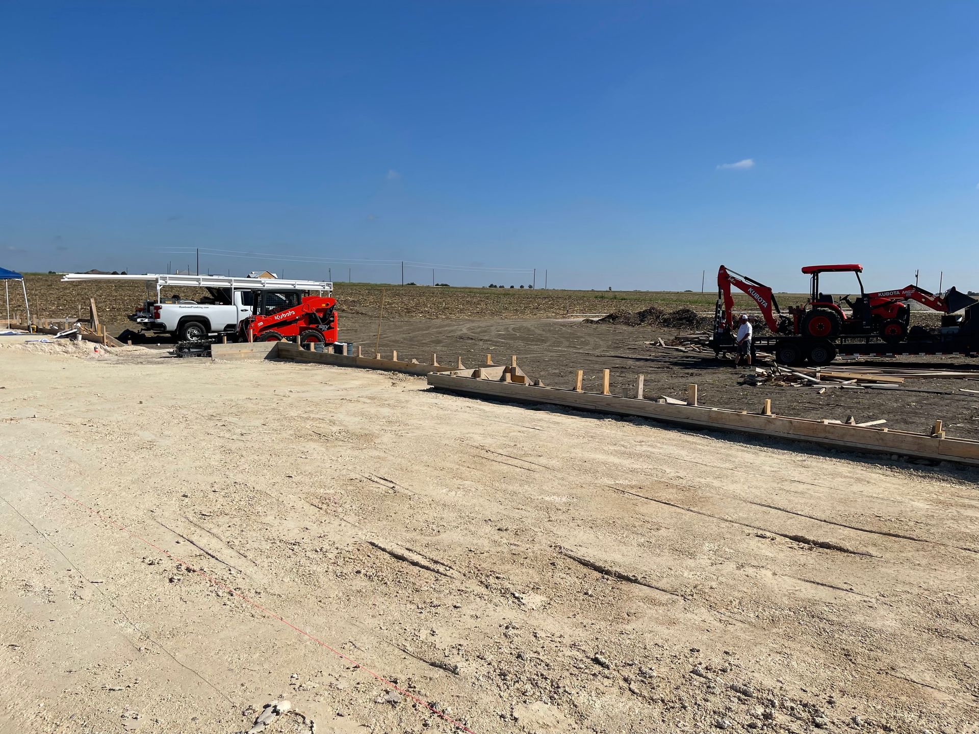 Construction equipment beside a gravel road in a barren landscape under a clear blue sky