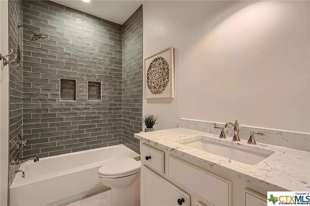 Modern bathroom with gray tile shower, white bathtub, and marble vanity with double sinks.