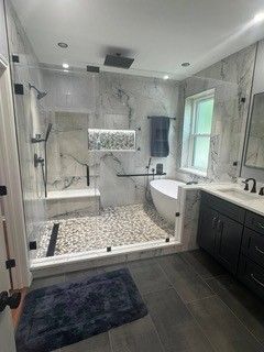 Modern bathroom with walk-in shower, freestanding tub, dark vanity, and gray marble tile.