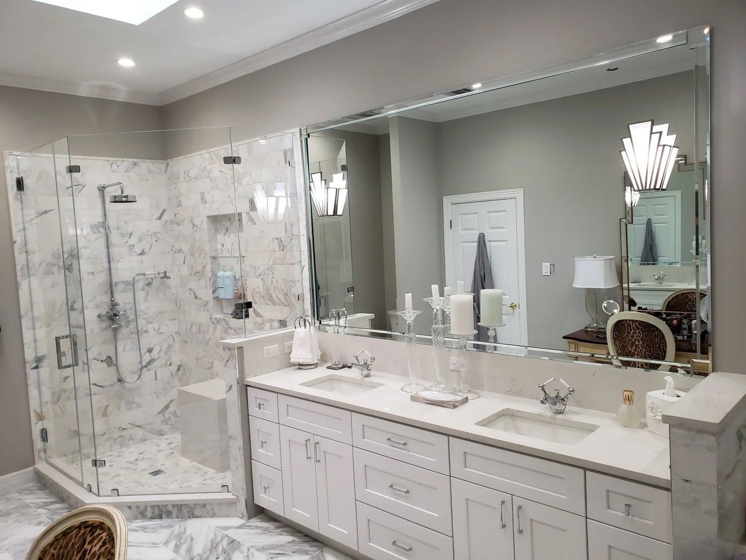 Elegant marble bathroom with glass shower, double vanity, and large mirror