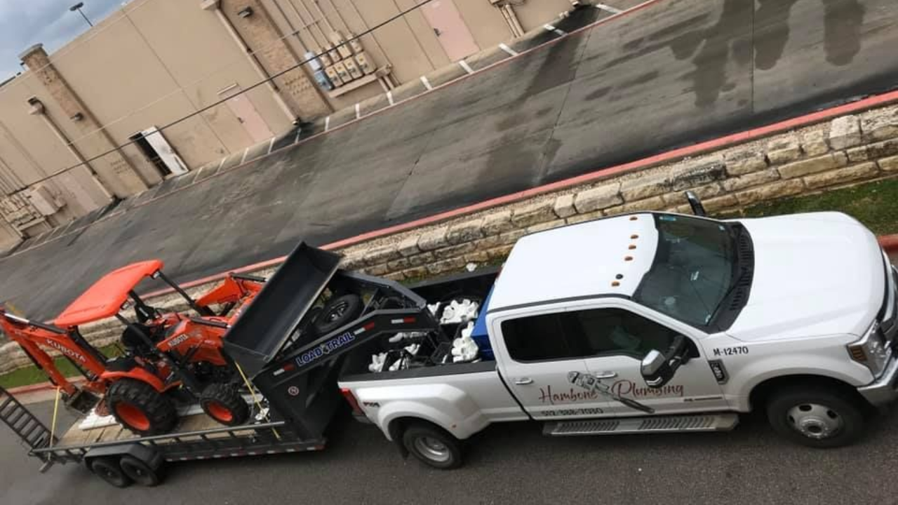 The Hambone Plumbing truck pulling a tractor