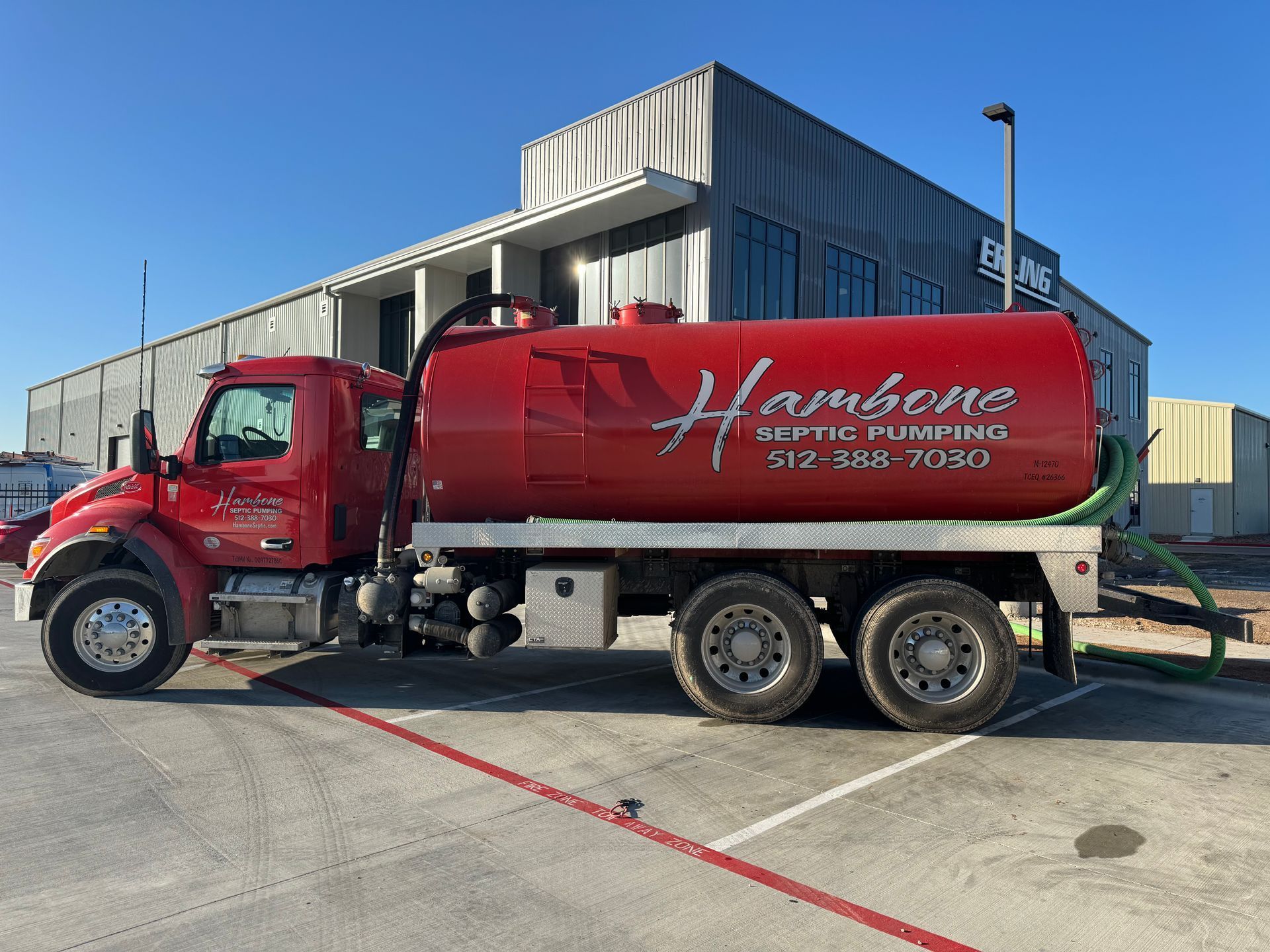 Red tanker truck parked outside a warehouse on a sunny day