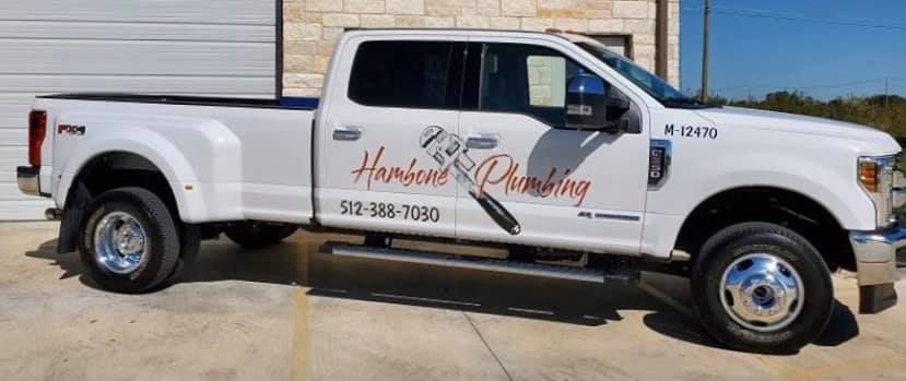White pickup truck with company logo and phone number parked outdoors by a building