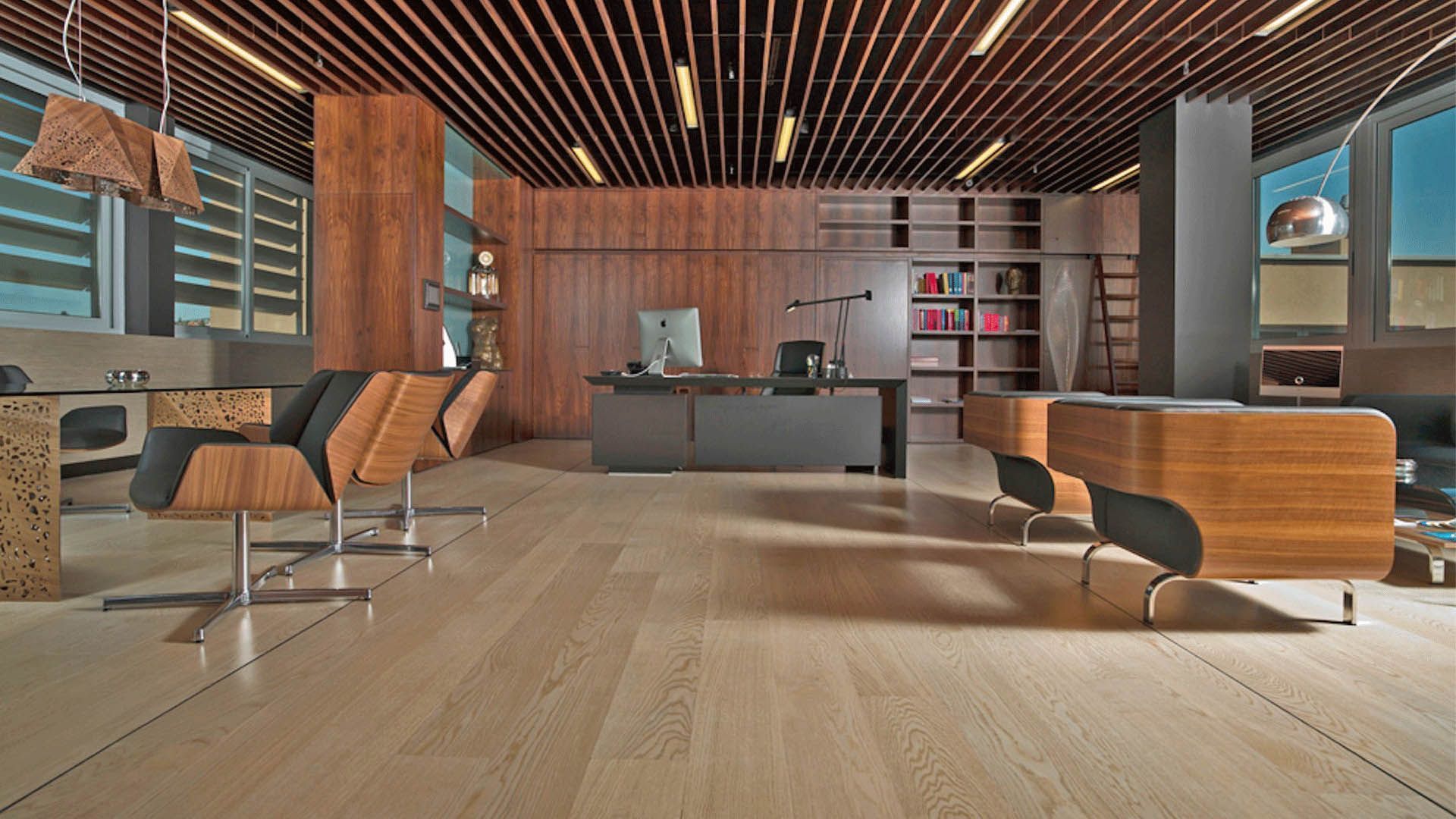 Modern office with wood accents: desk, chairs, bookshelves, and light-filled windows.
