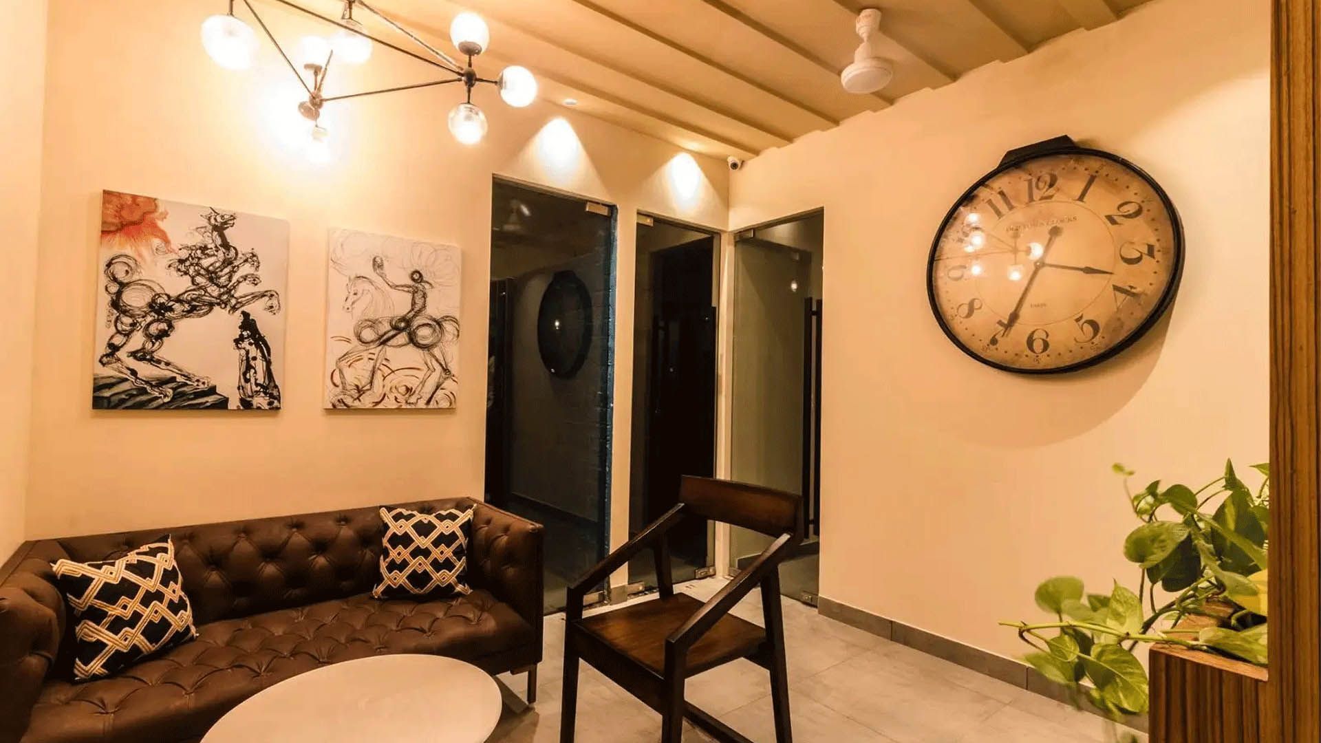Cozy living area with a brown sofa, art, a large clock, and a hanging light fixture.