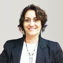 A woman wearing a black jacket and a white shirt is smiling for the camera.