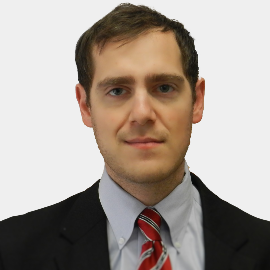 A man in a suit and tie looks at the camera