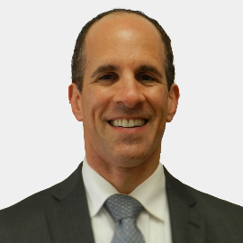 A man in a suit and tie smiles for the camera