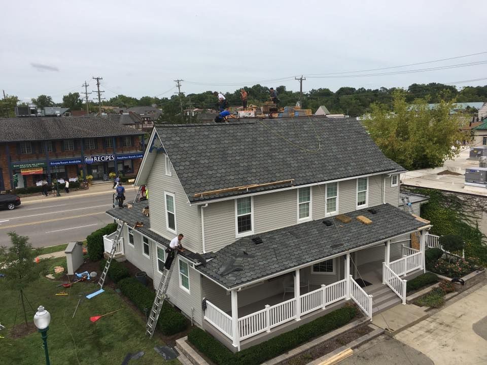 A group of people are working on the roof of a house.