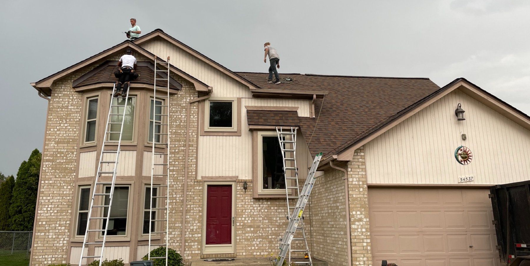 Two men are working on the roof of a house.