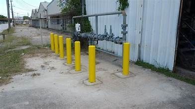 A row of yellow poles are lined up in front of a building.