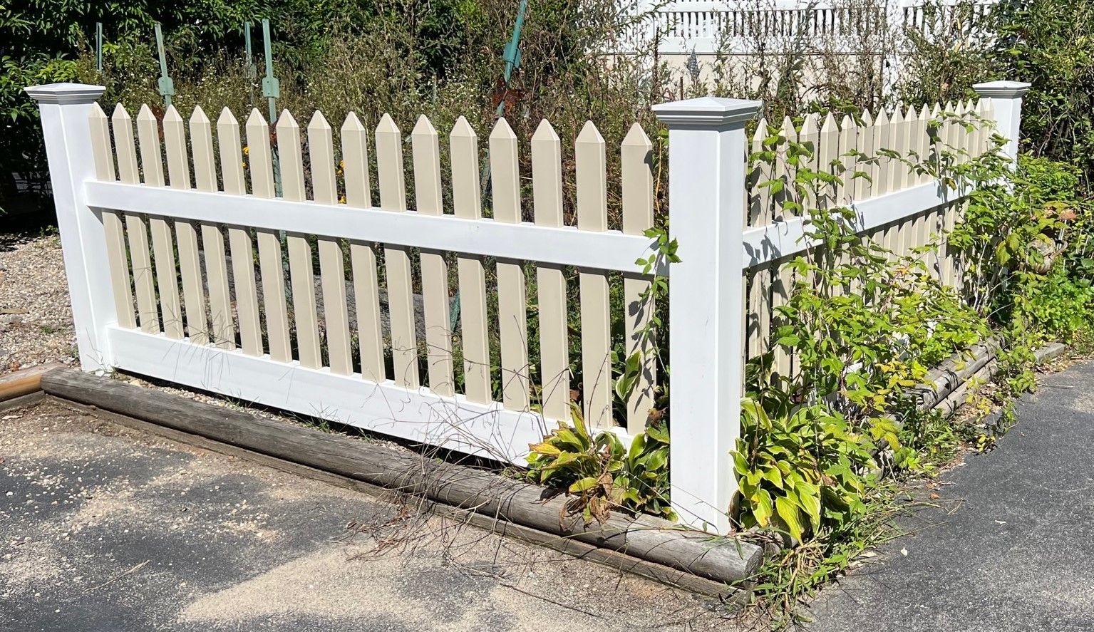 A white picket fence is sitting on the side of a road.