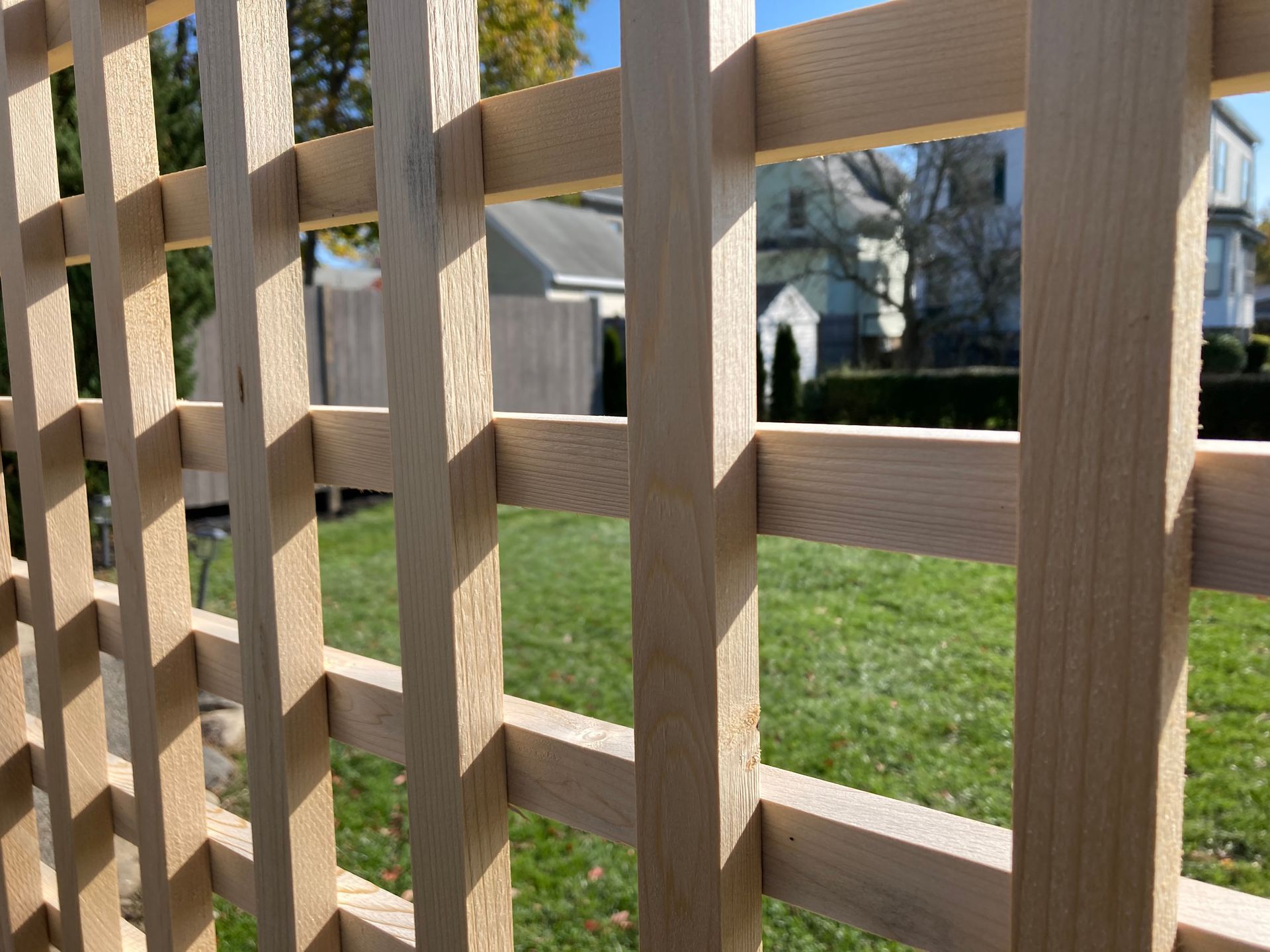 A close up of a wooden fence with a house in the background.