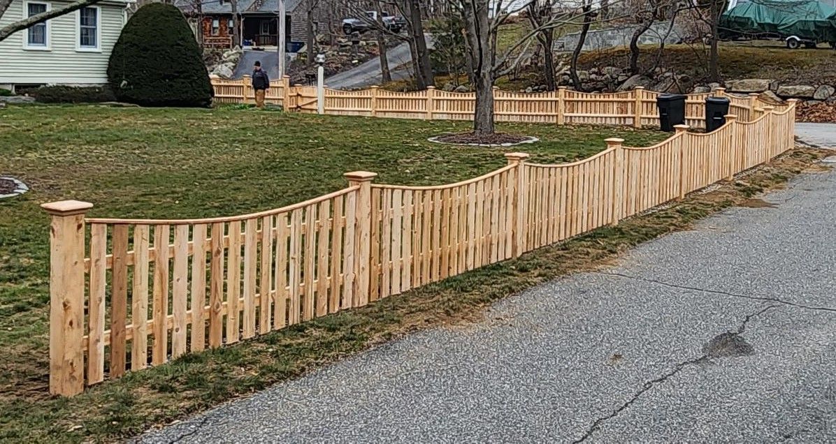 A wooden fence is sitting on the side of a gravel road.