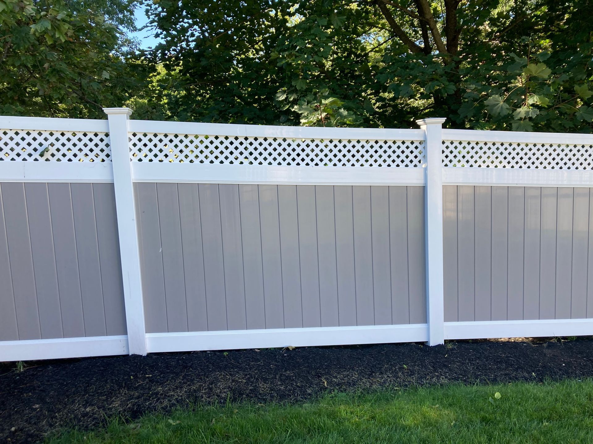 A white and gray fence with a lattice top
