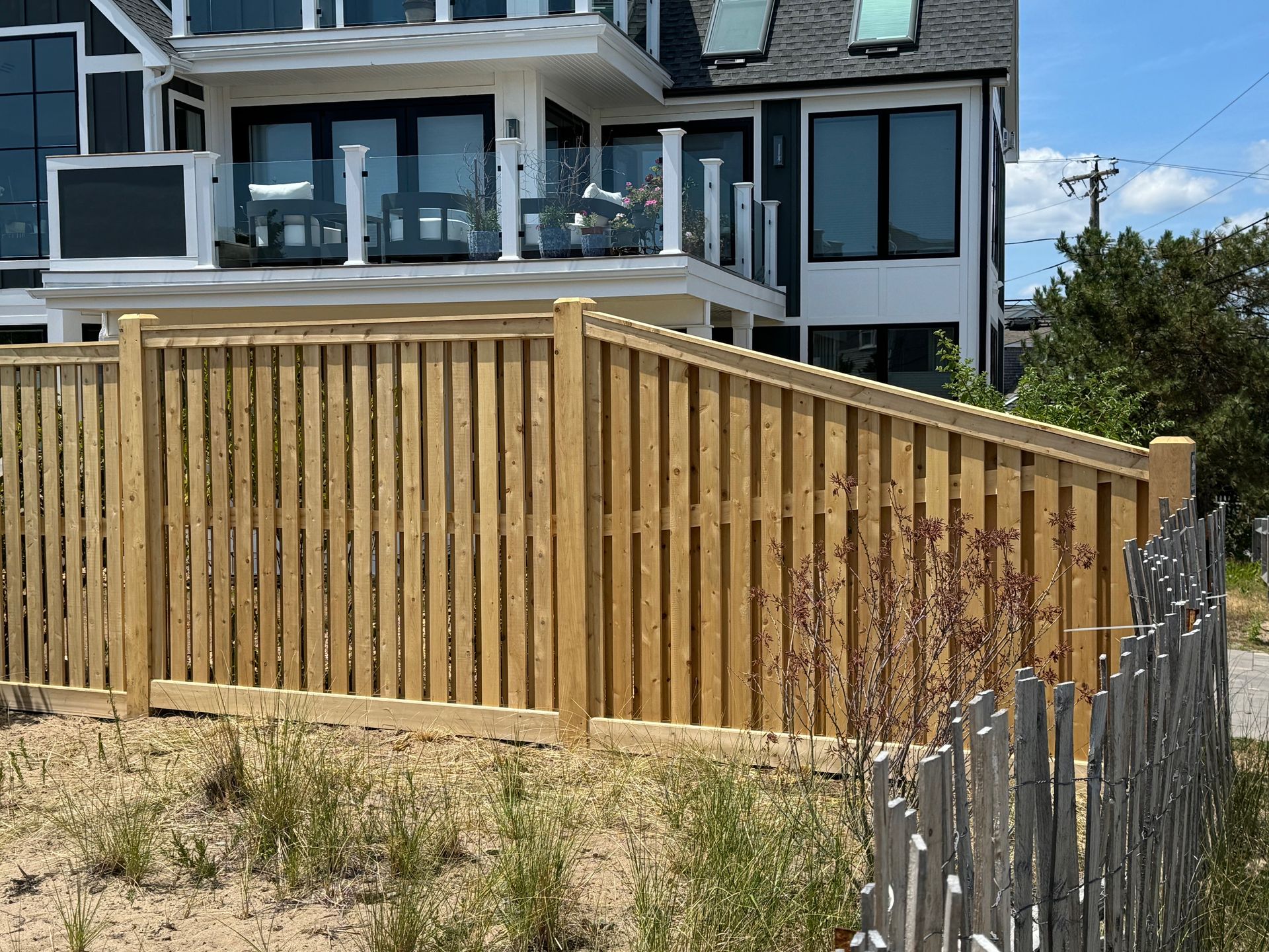 A wooden fence is in front of a large house.