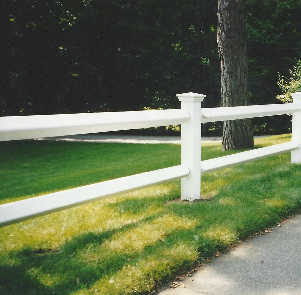 A white fence surrounds a lush green field