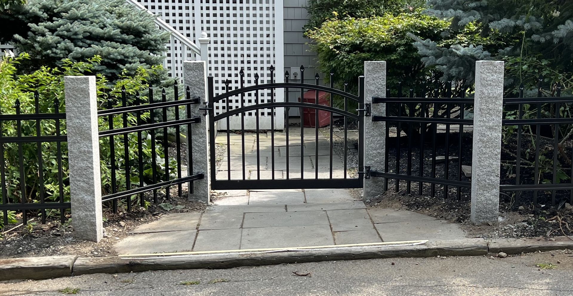 A wrought iron gate is open to a stone walkway