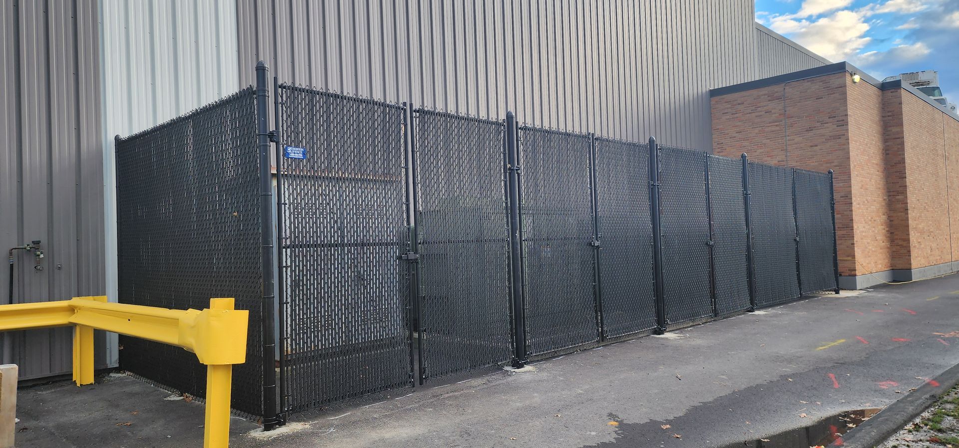 A black chain link fence is surrounding a brick building.
