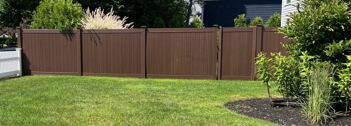 A wooden fence surrounds a lush green lawn in a backyard.