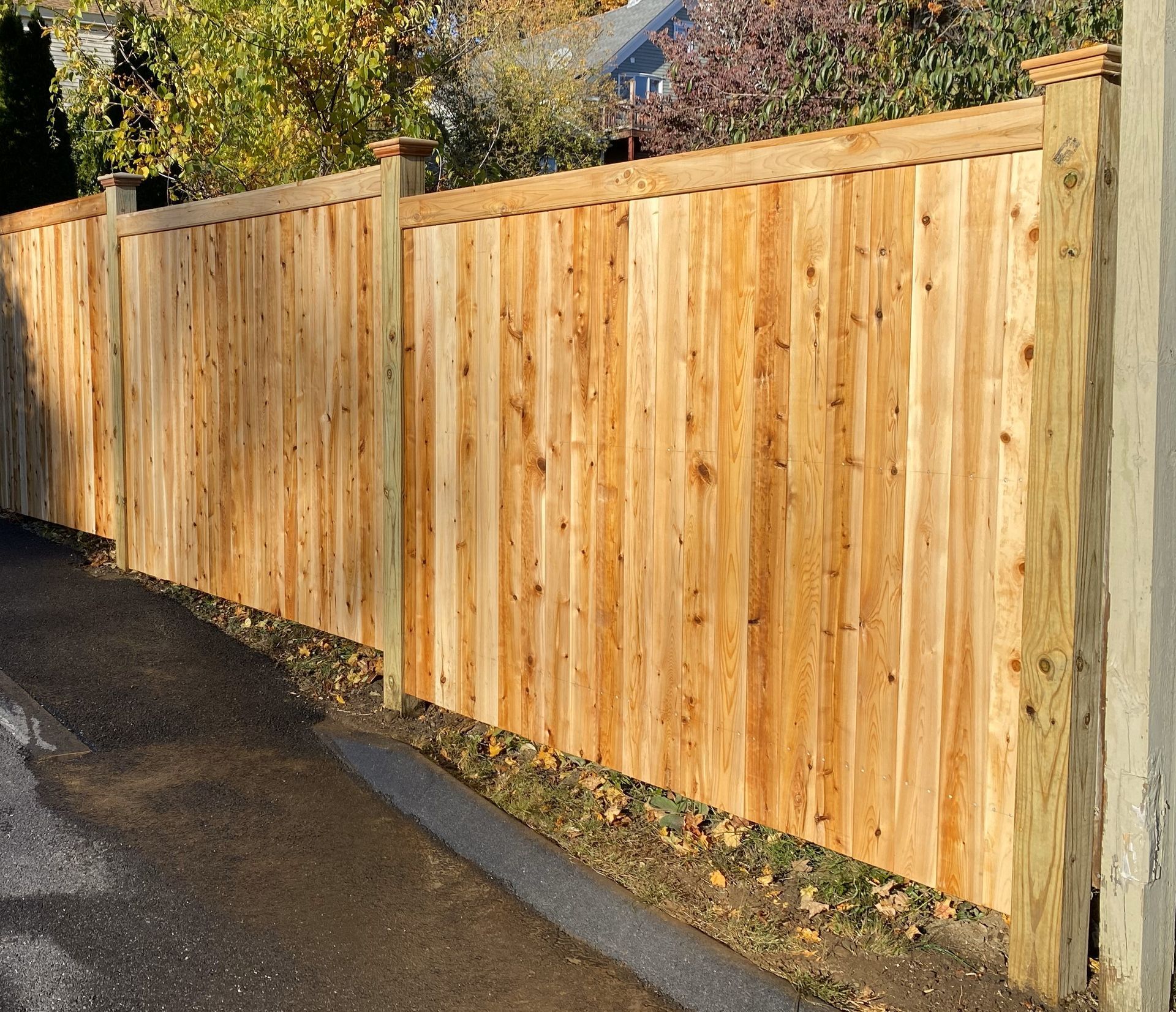 A wooden fence is along the side of a road