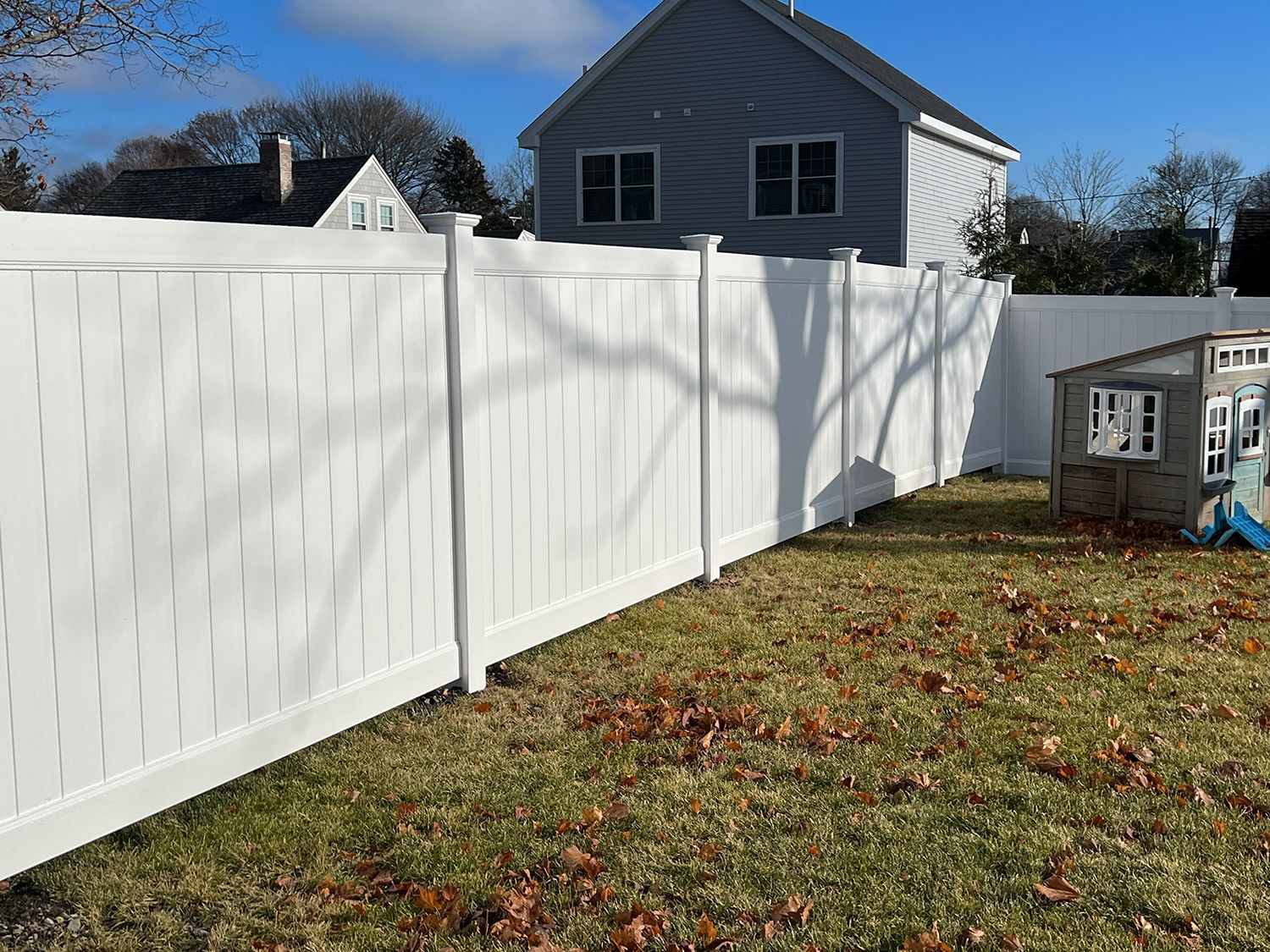 There is a white fence in the backyard of a house.