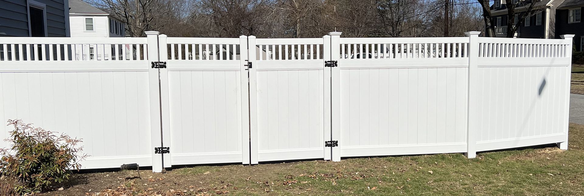 A white vinyl fence is sitting in the middle of a grassy yard.