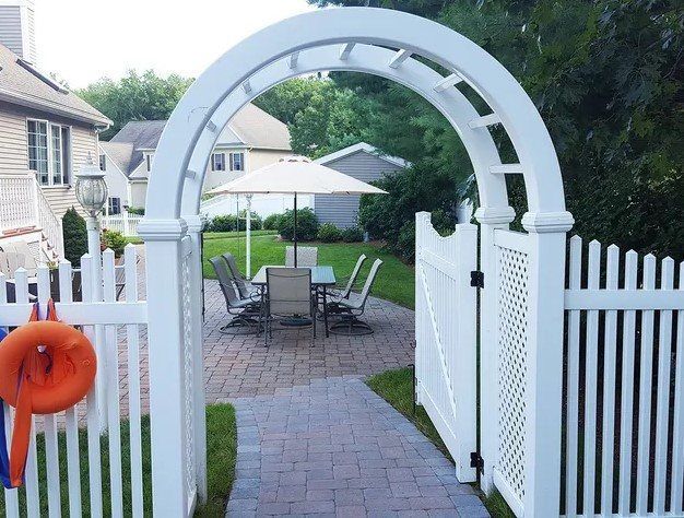 A white fence leading to a patio with a table and chairs