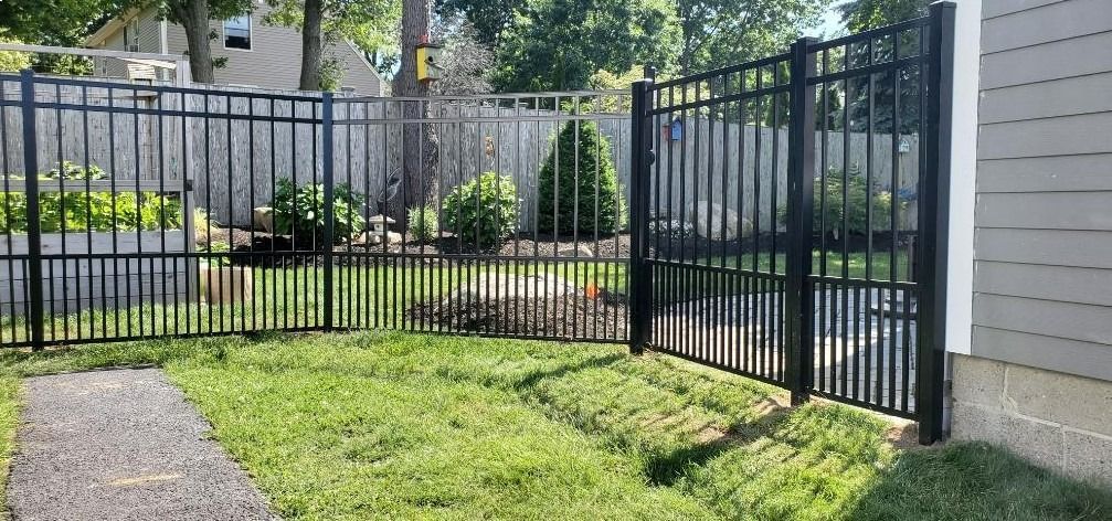 A black metal fence with a gate in the backyard of a house.
