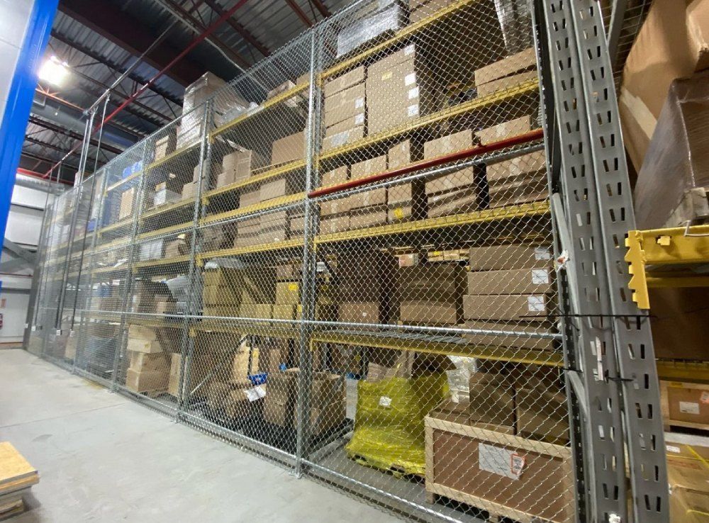 A warehouse filled with lots of shelves and boxes behind a chain link fence.