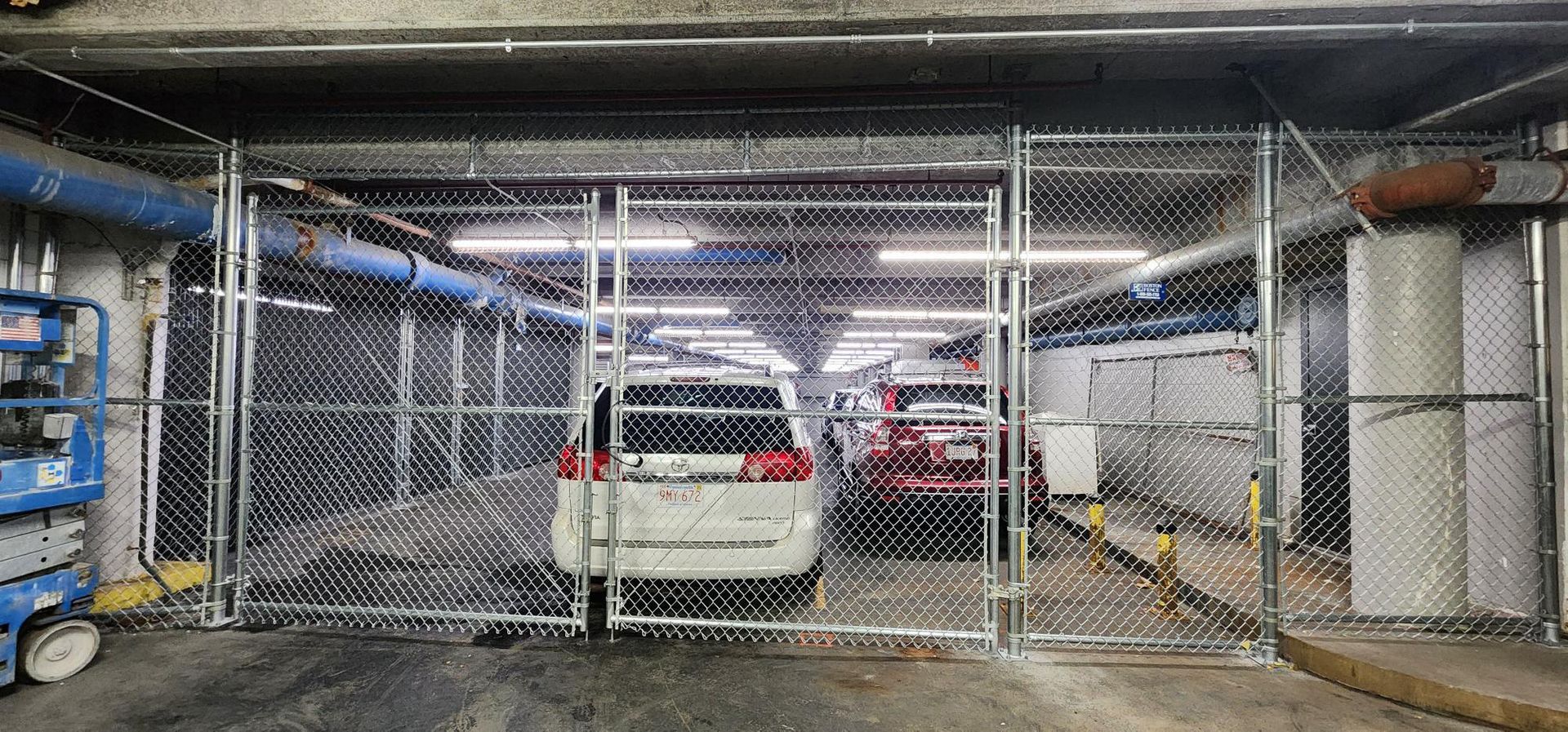 A parking garage with cars parked behind a chain link fence.