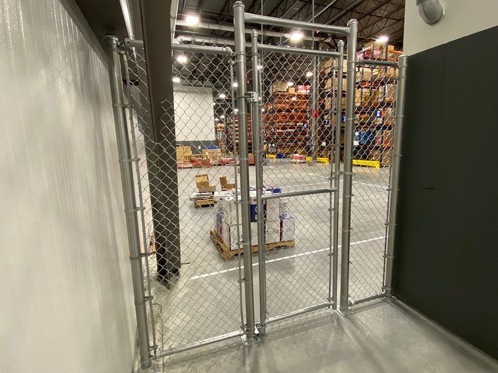 There is a chain link fence in the middle of a warehouse.