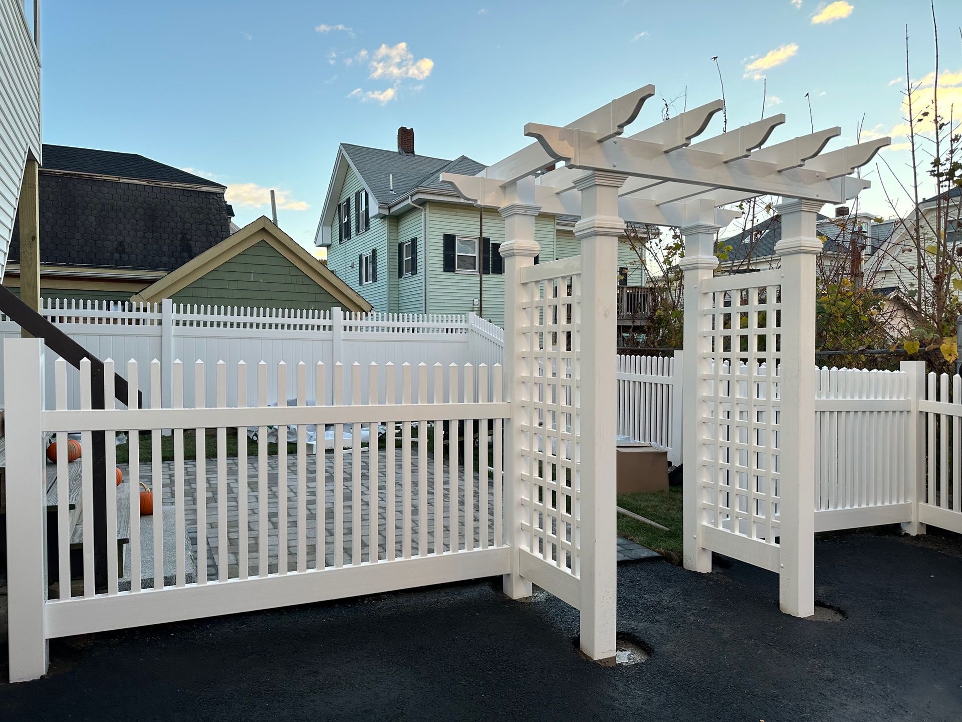 A white fence with a pergola in front of a house.