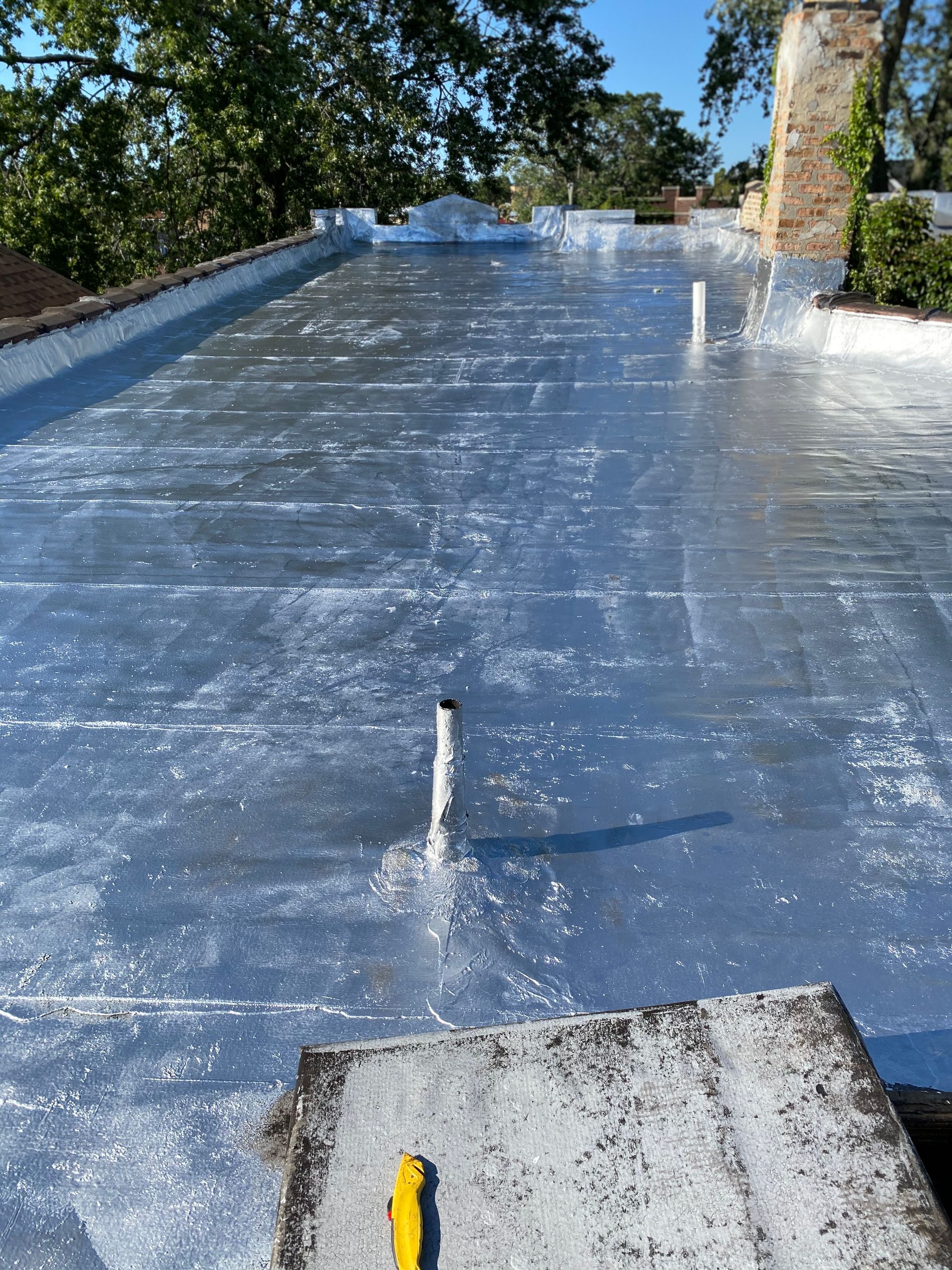 Flat roof with a white protective coating and a pipe.