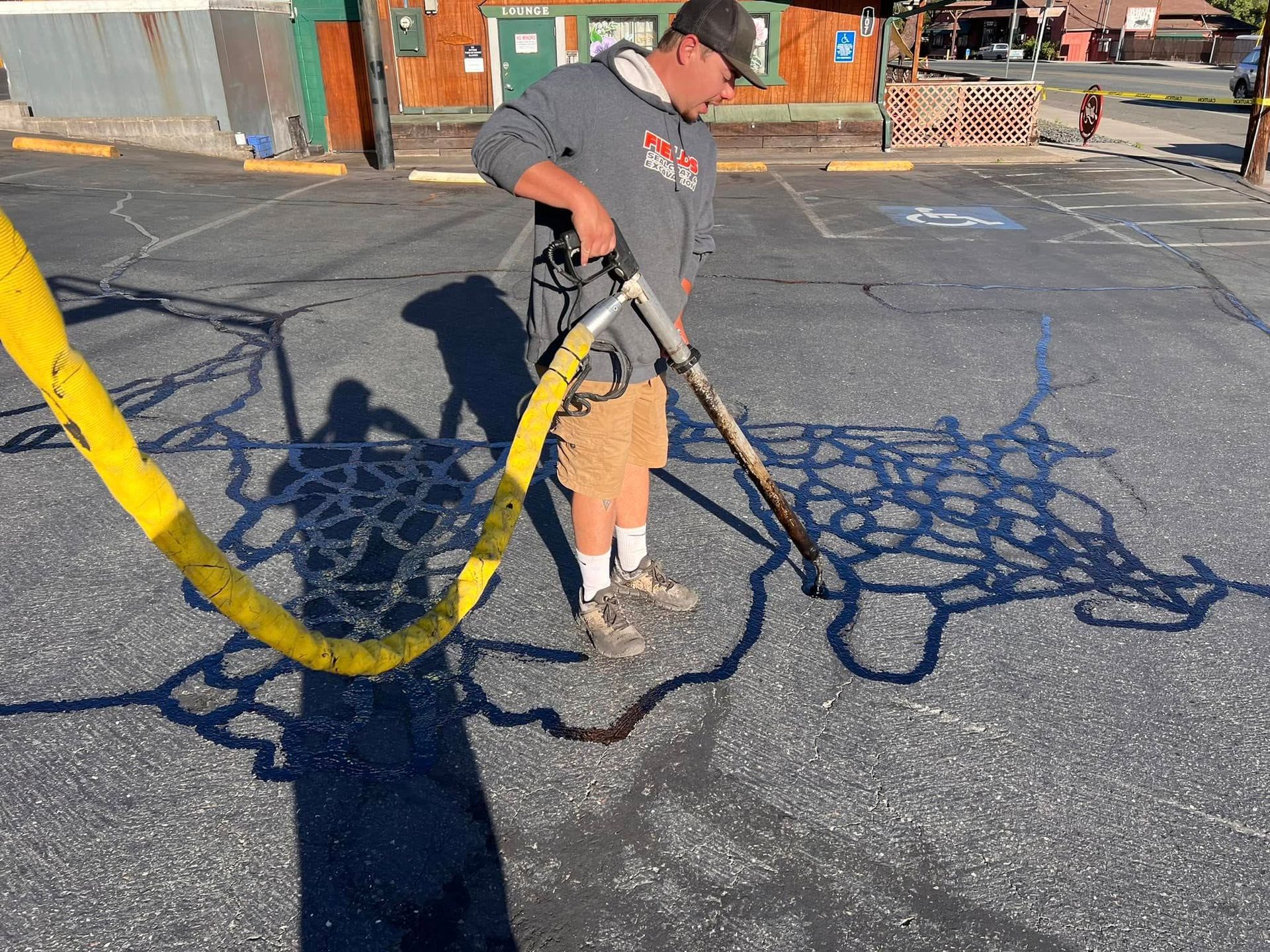 A man is using a hose to clean a parking lot.
