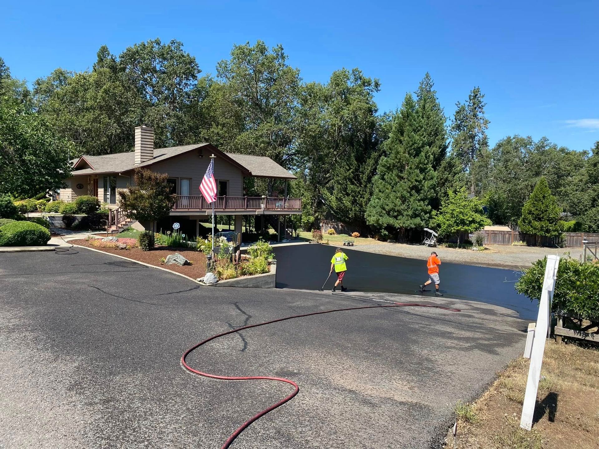 A couple of men are walking down a road in front of a house.