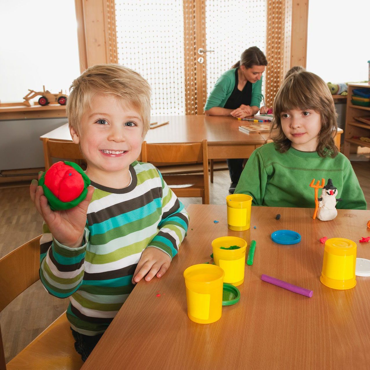 Children playing with colorful playdough at a table in a classroom