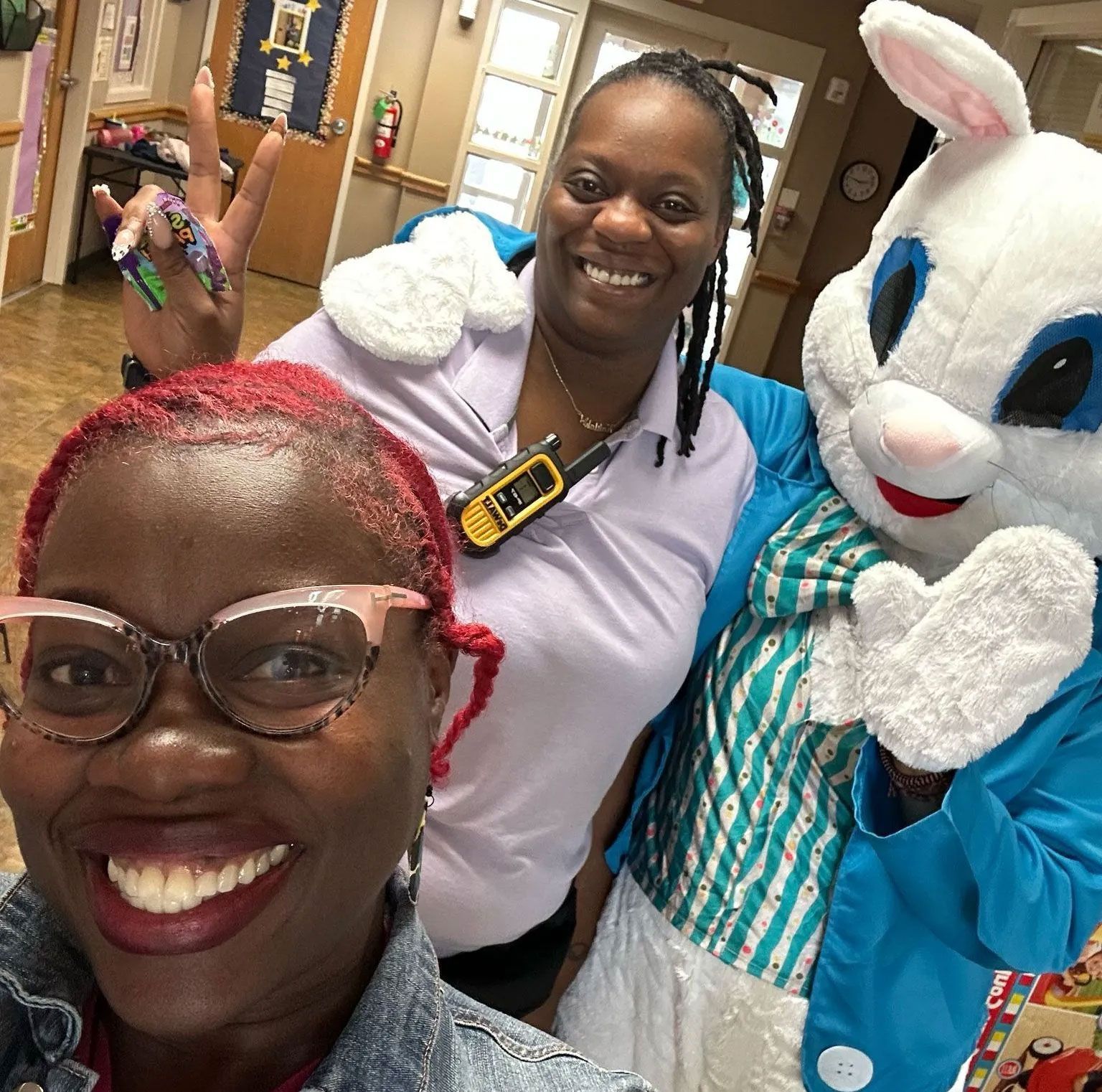 Two women are posing for a picture with a stuffed bunny