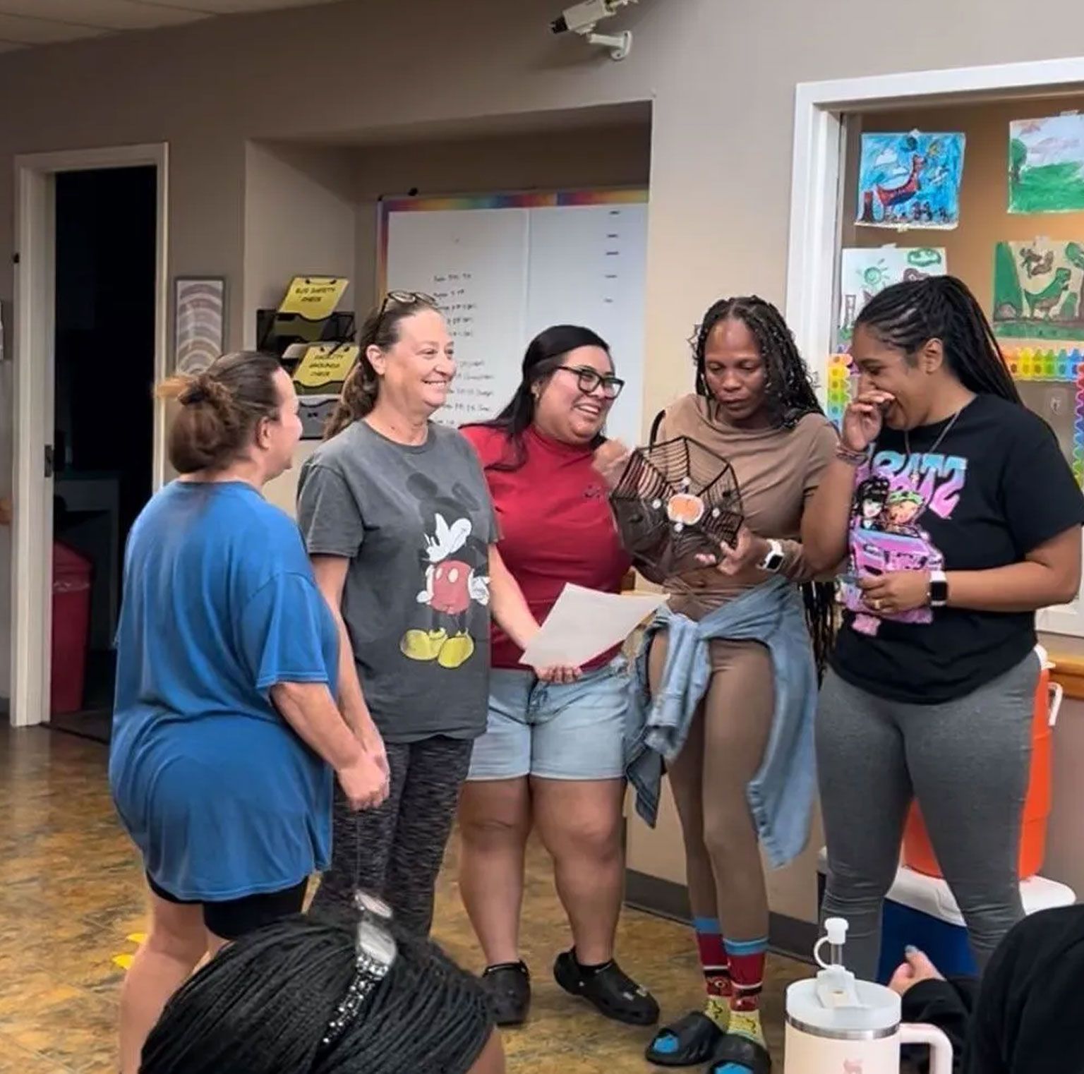 A group of women standing in a room with one wearing a mickey mouse shirt