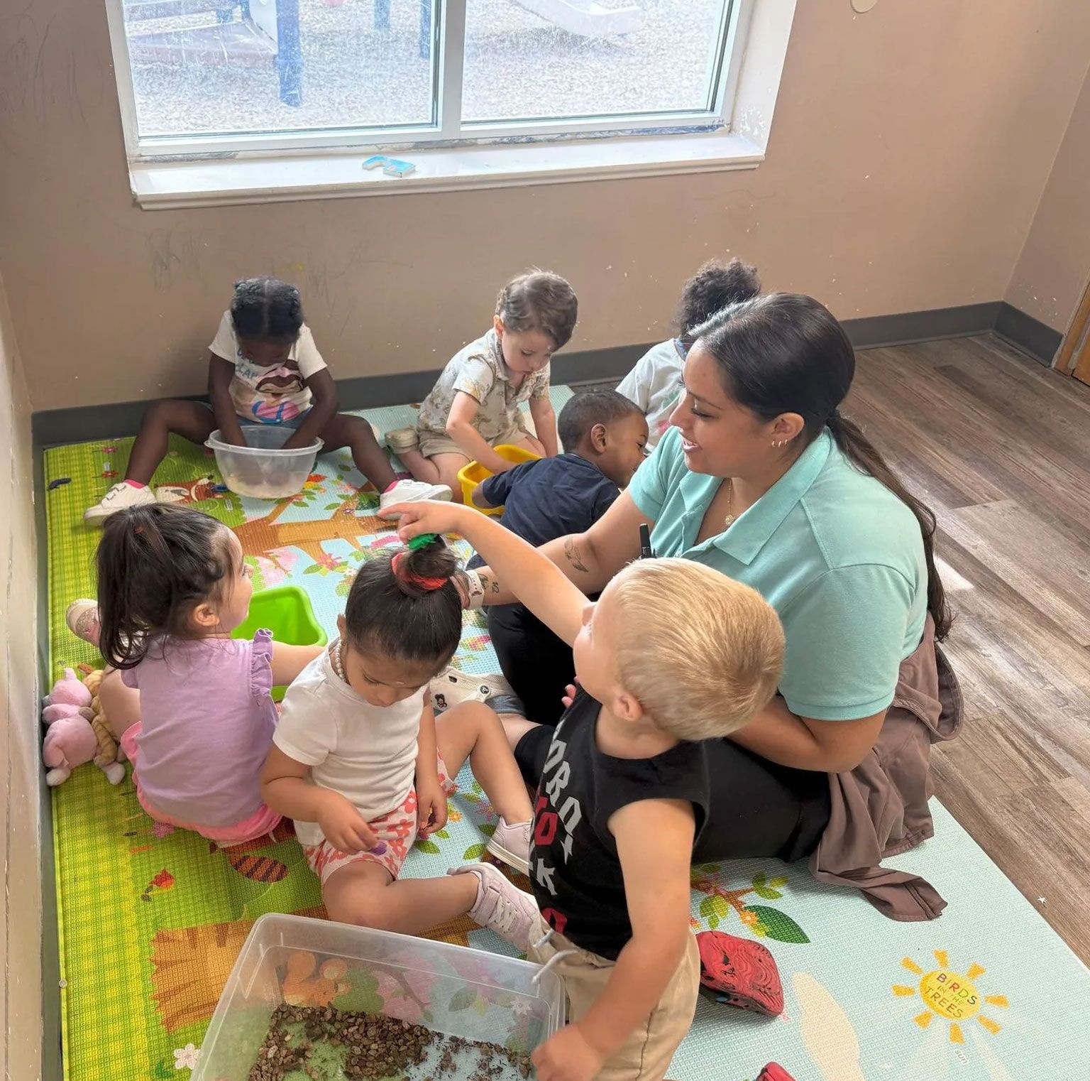 A woman is sitting on the floor with a group of children.
