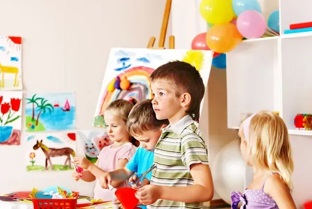 A group of children are making crafts in a classroom.