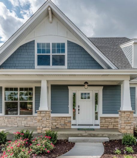 Blue and white house exterior with stone accents, a front porch, and a walkway.