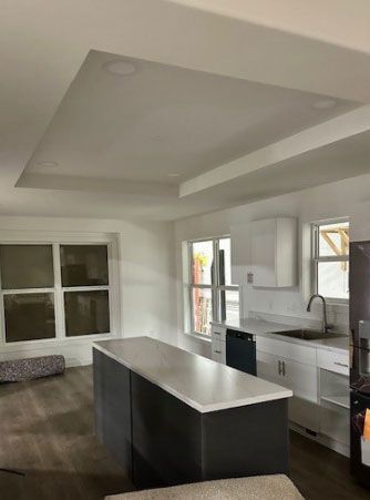Kitchen with island, white cabinets, and a coffered ceiling.