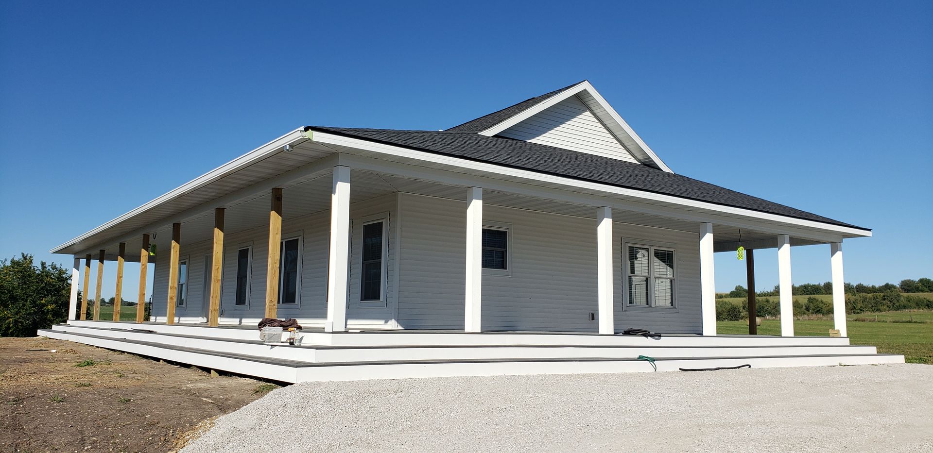 White house with porch; blue sky.